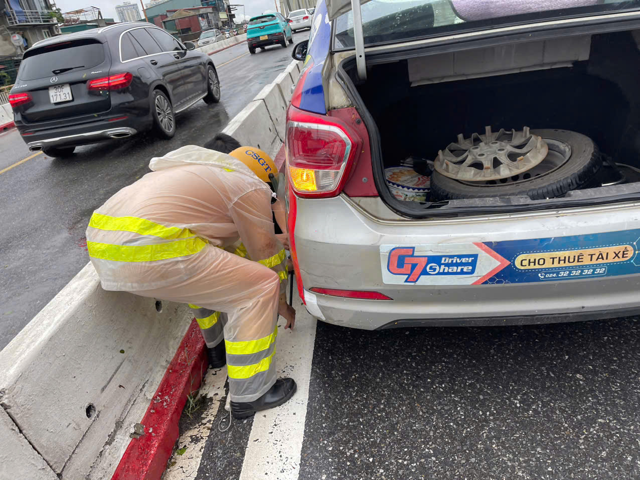 Cảnh sát giao thông đội mưa thay lốp xe cho người dân trên cầu Chương Dương - ảnh 1