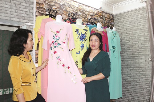 Chị Trần Thị Lan Hương (bên trái áo xanh) giới thiệu sản phẩm áo dài với ý tưởng sáng tạo thêu hoa lụa thu hút khách hàng
