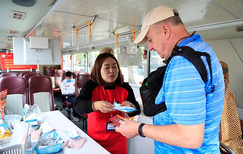 Khách quốc tế được phát khẩu trang khi sử dụng dịch vụ xe buýt 2 tầng tại Hà Nội