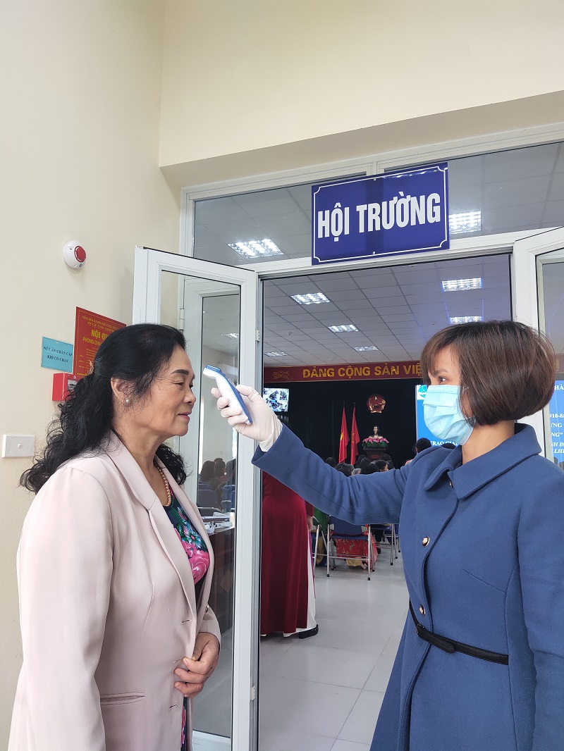 Cán bộ hội viên phụ nữ được kiểm tra thân nhiệt trước khi vào tham sự buổi lễ kỷ niệm nhằm đảm bảo an toàn sức khỏe cho mọi người phòng chống dịch Covid-19