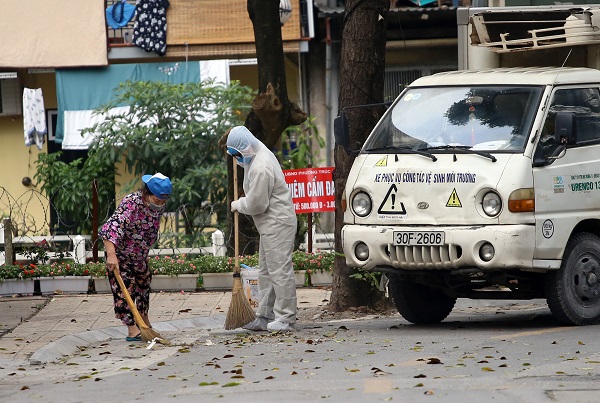 Nh&acirc;n vi&ecirc;n vệ sinh m&ocirc;i trường v&agrave; người d&acirc;n trong khu c&aacute;ch ly tại phố Tr&uacute;c Bạch c&ugrave;ng tham gia dọn vệ sinh m&ocirc;i trường