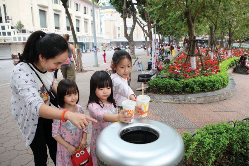 Hướng dẫn trẻ em bỏ rác đúng nơi quy định. Ảnh: Bùi Anh Tuấn
