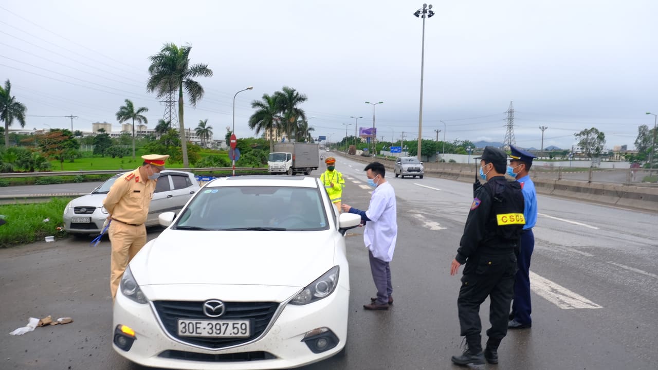 Lực lượng chức năng đang kiểm tra thân nhiệt của một tài xế tại điểm chốt cầu Thăng Long