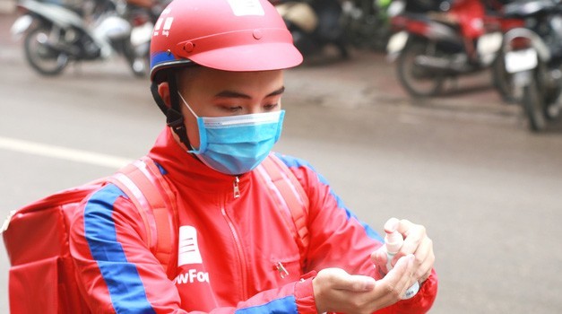 Nhân viên giao hàng qua mạng thực hiện sát khuẩn tay phòng chống dịch