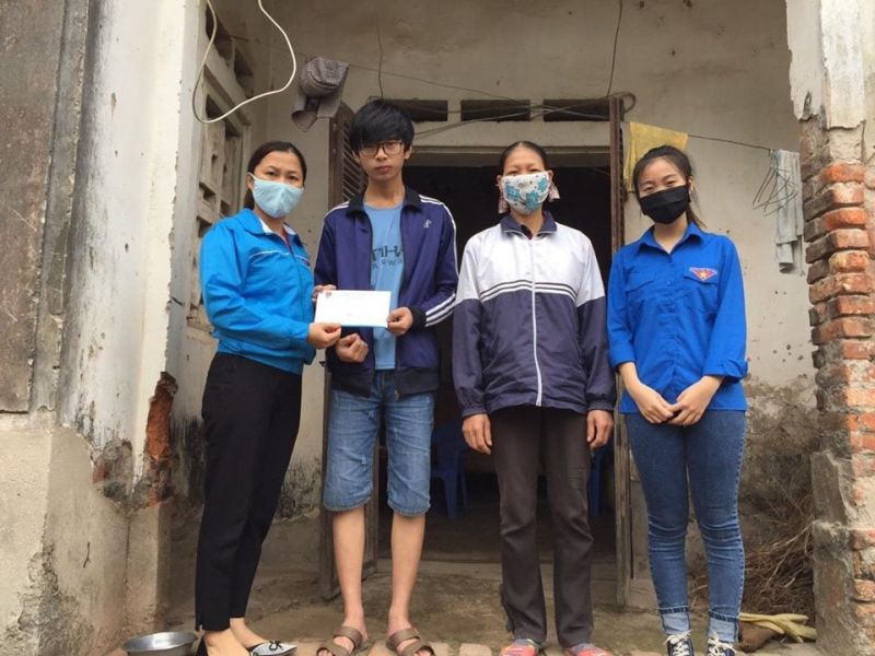 Cường và mẹ (hai người đứng giữa) nhận món quà của trường Đại học Công nghiệp Hà Nội, được hai đoàn viên xã Lê Ninh đại diện trao tặng