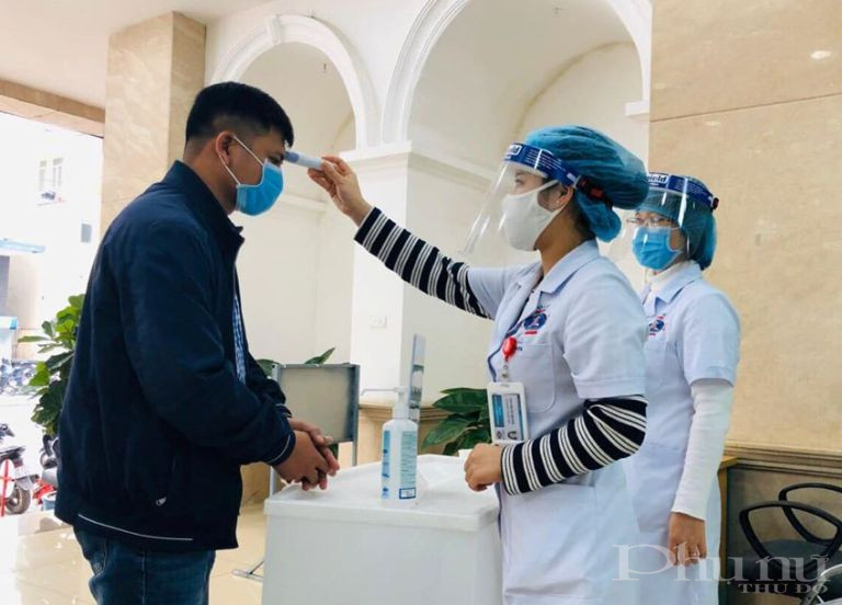 Bệnh nh&acirc;n v&agrave; người nh&agrave; bệnh nh&acirc;n được đo th&acirc;n nhiệt v&agrave; kh&aacute;m s&agrave;ng lọc khi đến thăm kh&aacute;m tại BV K Trung ương.