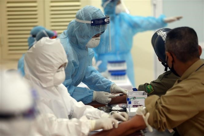 Các nhân viên y tế tiến hành xét nghiệm COVID-19 cho người dân tại chợ Ngã Tư Sở, Hà Nội ngày 19/4.