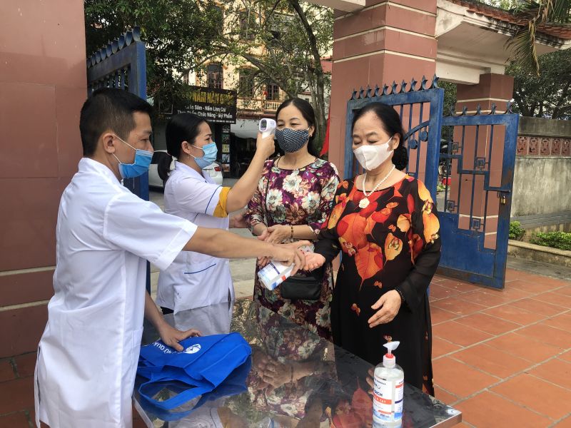 Hội vi&ecirc;n Hội LHPN quận H&agrave; Đ&ocirc;ng thực hiện nghi&ecirc;m việc đo th&acirc;n nhiệt, đeo khẩu trang v&agrave; s&aacute;t khuẩn tay trước khi dự Lễ b&aacute;o c&ocirc;ng d&acirc;ng B&aacute;c