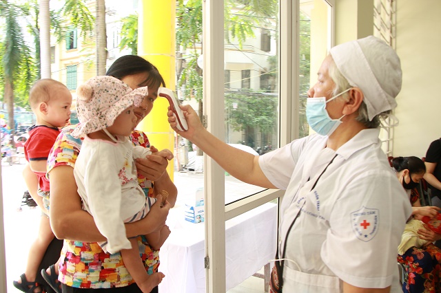 Tại điểm uống Vitamin A đặt tại Nhà văn hóa phường Nhân Chính, quận Thanh Xuân, bà mẹ và trẻ nhỏ đều được kiểm tra thân nhiệt để phòng chống dịch Covid-19. Đây là 1 trong 5 điểm uống Vitamin A trên địa bàn Phường.