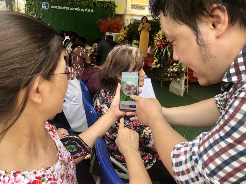 Một kỹ thuật viên đang hướng dẫn hội viên phụ nữ cách cài đặt và sử dụng App Chonhaminh.gov.vn