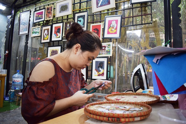 Nhân viên HTX Vụn Art say sưa cắt dán các chi tiết từ vải lụa để tạo thành những bức tranh dân gian độc đáo