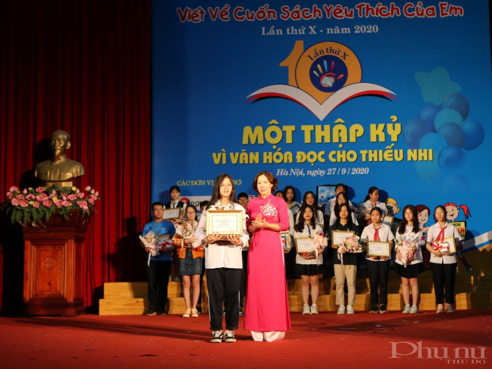 Bà Lê Kim Anh - Chủ tịch Hội LHPN Hà Nội trao giải Nhất cho tác giả Hoàng Minh Phúc - lớp 8A3, trường THCS Trung Hòa (Hà Nội), viết về tác phẩm “Dòng sông thơ ấu”. (Ảnh: Nguyễn Thực)