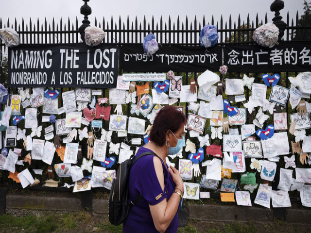 Người phụ nữ đi qua bức tường tưởng niệm người chết vì Covid-19 ở nghĩa trang Green-Wood, hạt Brooklyn, thành phố New York hôm 28/5. Ảnh: AP.