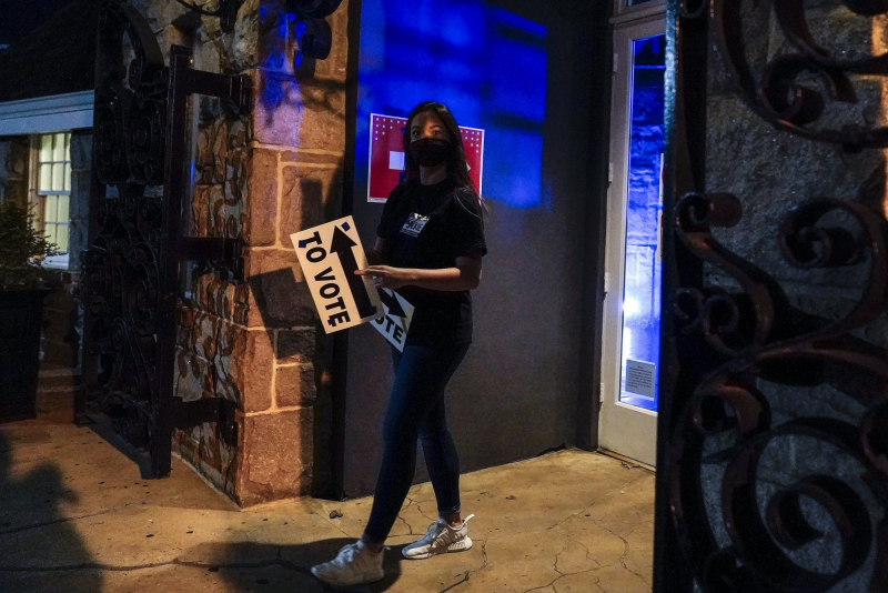 Một nhân viên thăm dò ý kiến bước ra khỏi khu bầu cử với tấm biển 