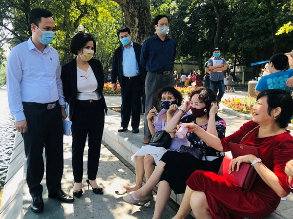 Đoàn kiểm tra số 2 của Sở Y tế nhắc nhở người dân đeo khẩu trang phòng dịch bệnh Covid-19 khi tham gia đi dạo tại Bờ Hồ, quận Hoàn Kiếm. Ảnh: Văn Lập