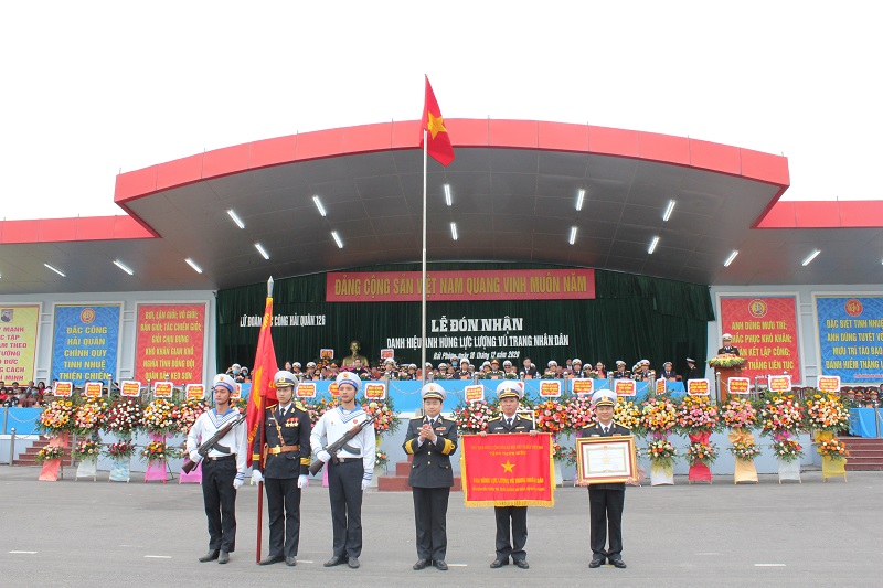 Thừa ủy quyền của Chủ tịch nước, Chuẩn đ&ocirc; đốc Trần Thanh Nghi&ecirc;m đ&atilde; gắn hu&acirc;n chương l&ecirc;n qu&acirc;n kỳ, trao cờ, bằng chứng nhận Anh h&ugrave;ng LLVT nh&acirc;n d&acirc;n cho đại diện chỉ huy đơn vị.