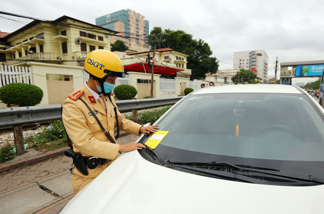 Cảnh s&aacute;t giao th&ocirc;ng (C&ocirc;ng an th&agrave;nh phố H&agrave; Nội) d&aacute;n th&ocirc;ng b&aacute;o &ldquo;phạt ngu&ocirc;̣i&rdquo; l&ecirc;n một xe &ocirc; t&ocirc; vi phạm lỗi dừng, đỗ sai quy định tại quận Đống Đa.