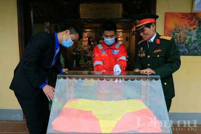 Đồng chí Phan Sỹ Linh, Phó Bí thư Thường trực Đoàn Thanh niên Tập đoàn Dầu khí Quốc gia Việt Nam và cựu chiến binh mặt trận Vị Xuyên kính cẩn đưa lá cờ vào tủ kính lưu trữ tại Đài hương 468.