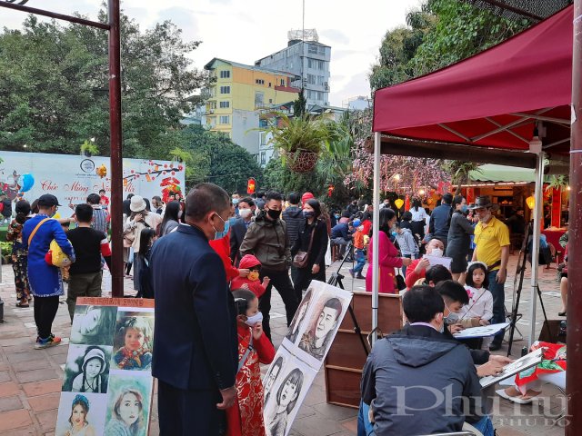 Một h&agrave;ng vẽ tranh truyền thần thu h&uacute;t nhiều người xem tại khu vực Hồ Văn.