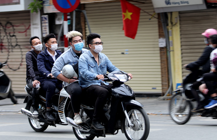 Người điều khiển xe m&aacute;y mặc d&ugrave; cầm mũ, nhưng kh&ocirc;ng đội.