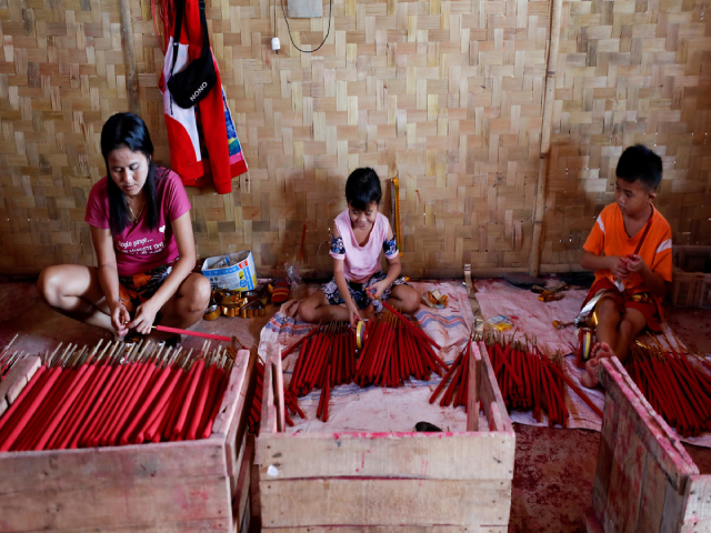 Alen Lenni (trái) và hai con sản xuất các que hương lớn trong xưởng tại gia ở ngoại ô thủ đô Jakarta của Indonesia.