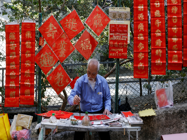 Người đàn ông viết thư pháp trên giấy đỏ trên một con phố ở Hong Kong.