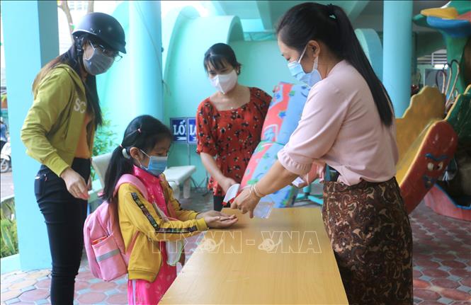Giáo viên Trường Mầm non Hoa Lan thành phố Vĩnh Long đo thân nhiệt, rửa tay cho trẻ trước khi vào lớp. Ảnh: Lê Thúy Hằng/TTXVN