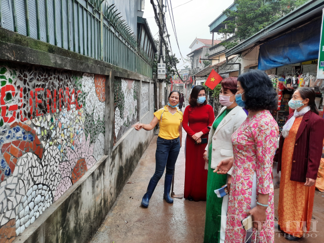 Chị Hiên đang say sưa giới thiệu về bức bích hoạ trên tường đường làm từ hàng ngàn mảnh sành, sứ vỡ.