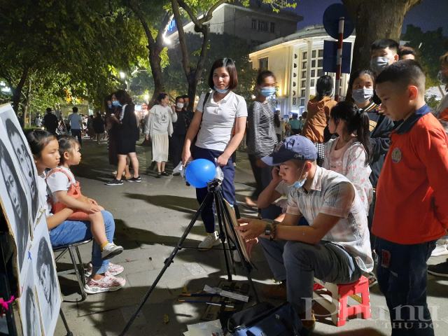 Người dân xem vẽ truyền thần tại phố đi bộ.