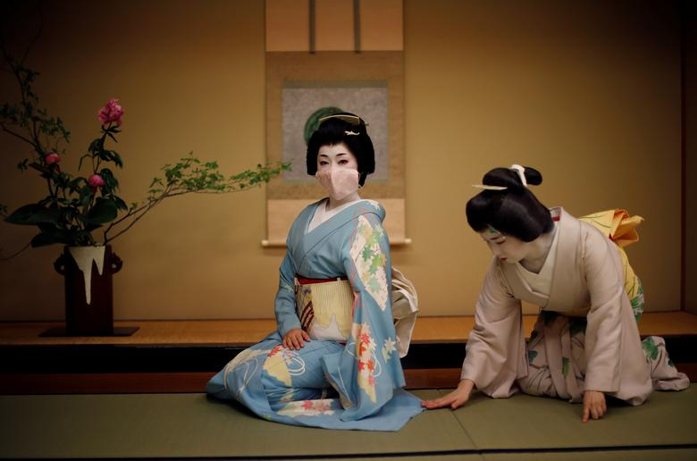 Mayu chỉnh trang kimono cho Koiku, khi Koiku bận tạo dáng chụp ảnh. Hai geisha chuẩn bị biểu diễn tại một bữa tiệc ở nhà hàng sang trọng giữa phố thị Tokyo, Nhật Bản.