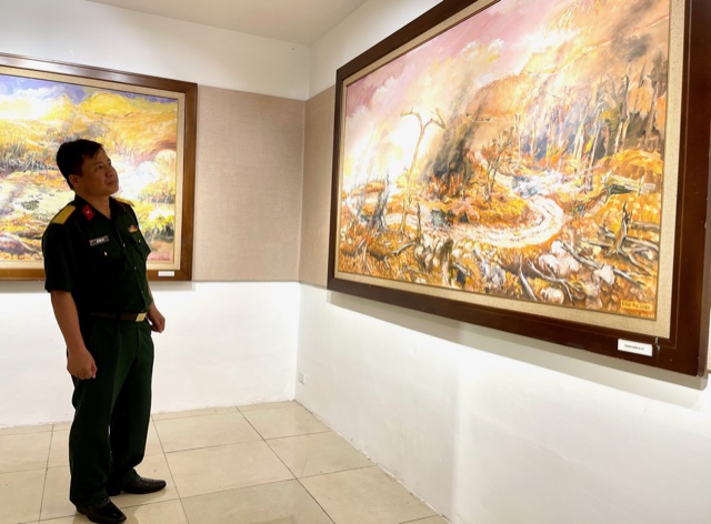 Một người lính thời bình trước bức tranh rừng Trường Sơn khói lửa ngày ấy. Ảnh: VGP/Nhật Nam
