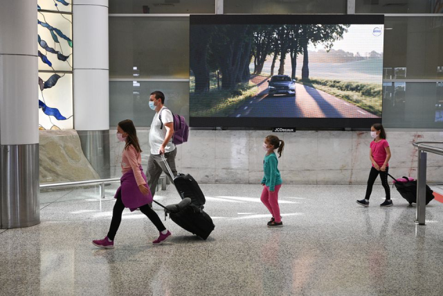 Du khách đeo khẩu trang đi qua khu vực đón khách của nhà ga quốc tế Kingsford Smith.