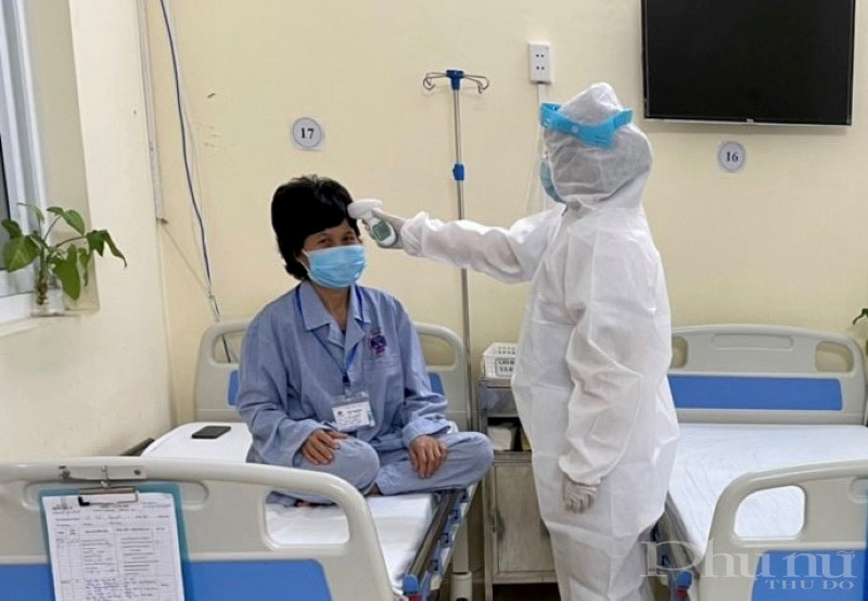 Điều dưỡng viên BV K hỗ trợ đo thân nhiệt hàng ngày cho người bệnh.