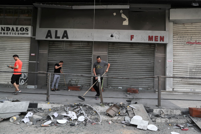 Người Palestine dọn dẹp các mảnh vỡ tại địa điểm xảy ra cuộc không kích của Israel.