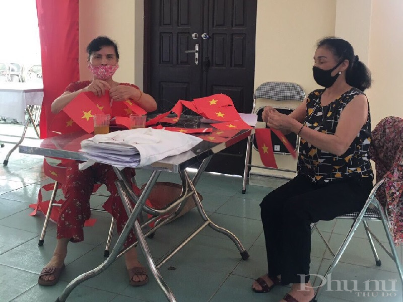 Cán bộ, hội viên phụ nữ dán cờ để trang trí đường phố, điểm bỏ phiếu trong ngày hội bầu cử toàn dân.