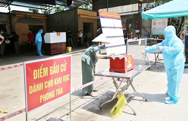 Cử tri tại một khu vực phong tỏa thực hiện quyền bầu cử của m&igrave;nh.  Ảnh: Int.