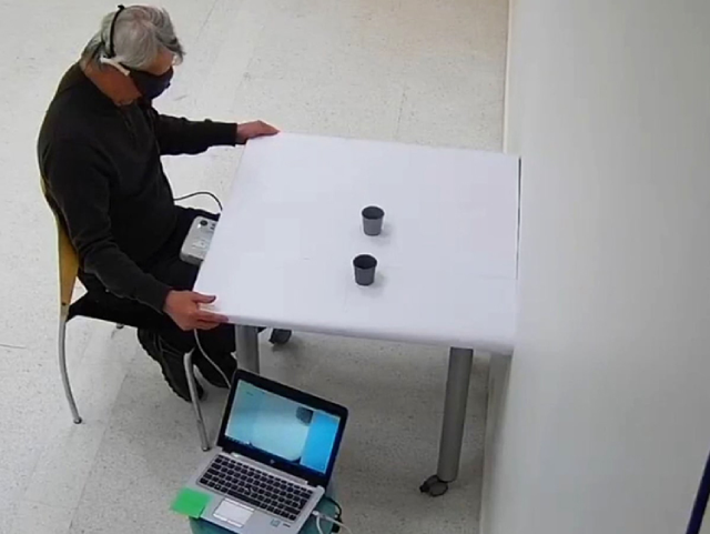 Thiết bị kính phát sáng giúp bệnh nhân khiếm thị có thể xác định vị trí và chạm vào quyển sách trên bàn - Ảnh: Nytimes.com