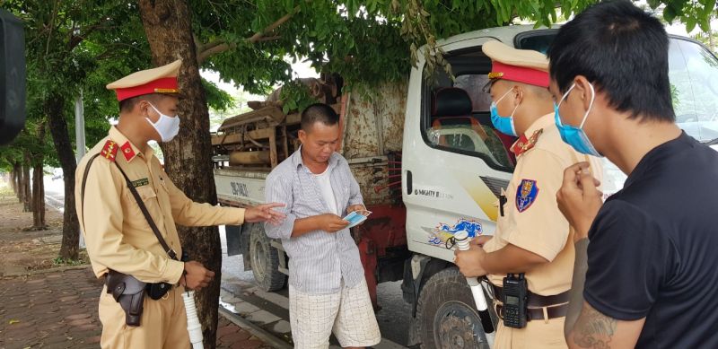 Cán bộ CSGT tặng khẩu trang cho người ngồi ghế phụ trên xe và nhắc nhở đeo khẩu trang nghiêm túc
