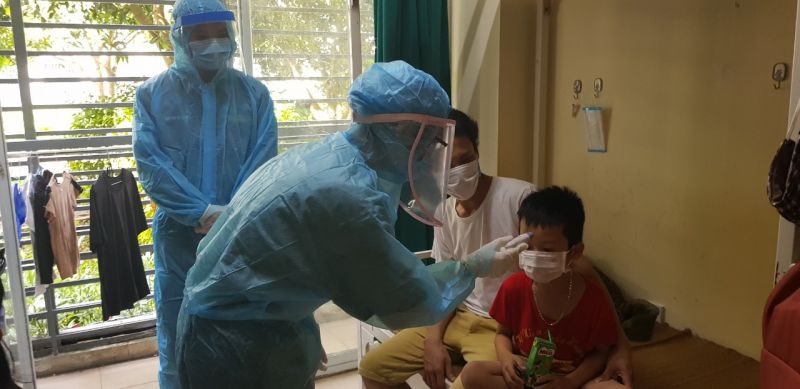 C&aacute;n bộ y tế đo nhiệt độ cho ch&aacute;u Đỗ Thế Bảo Minh (6 tuổi) con anh Đỗ Thế To&agrave;n