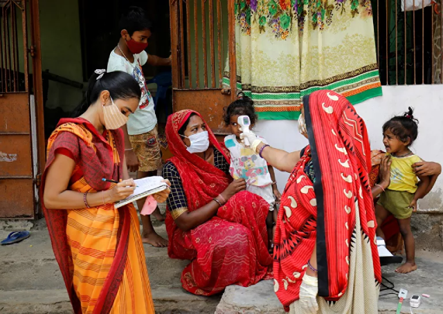 Một nh&acirc;n vi&ecirc;n y tế kiểm tra nhiệt độ của người d&acirc;n trong l&agrave;ng ở ngoại &ocirc; Ahmedabad, Ấn Độ.