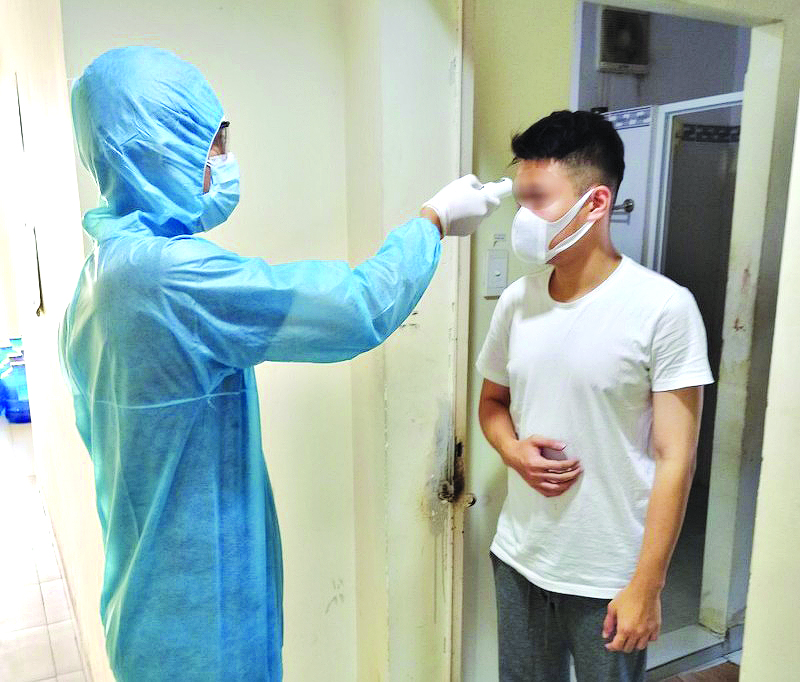 Nh&acirc;n vi&ecirc;n y tế đo th&acirc;n nhiệt cho người c&aacute;ch ly tập trung tại K&yacute; t&uacute;c x&aacute; đại học Quốc gia TP.HCM (Ho&agrave;ng Lan)
