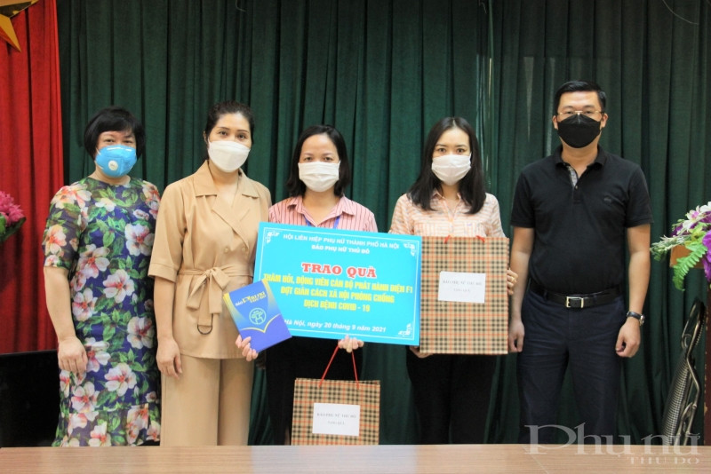 Phó Tổng biên tập Báo Phụ nữ Thủ đô Lê Thị Hồng Minh (thứ 2 từ trái qua) tặng quà cho chị Vũ Thị Dung.