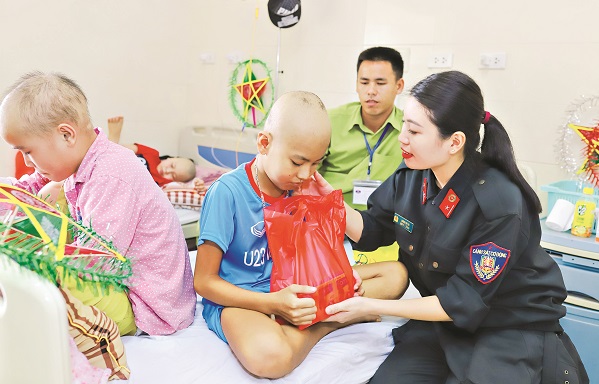 Trung úy Lương Thị Thu trao quà cho các cháu nhỏ bị bệnh ởbệnh viện K