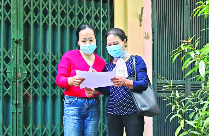 Bà Phạm Thị Hoán - Chi hội trưởng Chi hội Phụ nữ số 4 (Hội LHPN phường Bưởi, quận Tây Hồ) tới từng gia đình phát phiếu và hướng dẫn đăng ký tiêm vắc-xin cho trẻ em Ảnh: NVCC