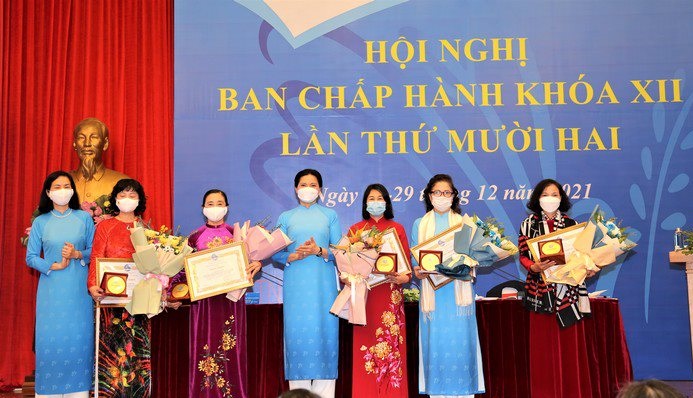 Đồng chí Hà Thị Nga, Chủ tịch Hội LHPN Việt Nam người thứ 4 từ phải sang và đồng chí Nguyễn Thị Minh Hương, Phó Chủ tịch Hội LHPN Việt Nam người đầu bên trái trao