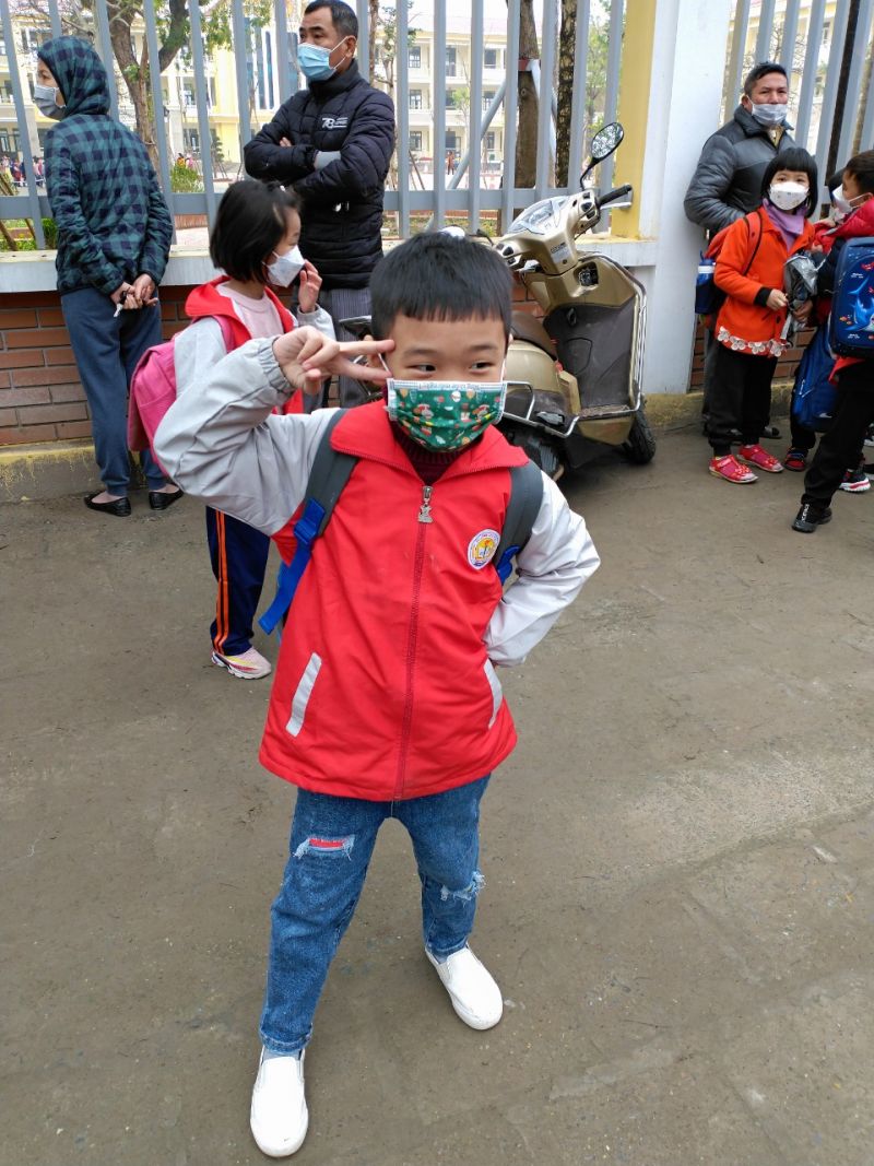 Một học sinh nhí trường tiểu học Đại Áng làm dáng trước cổng trường