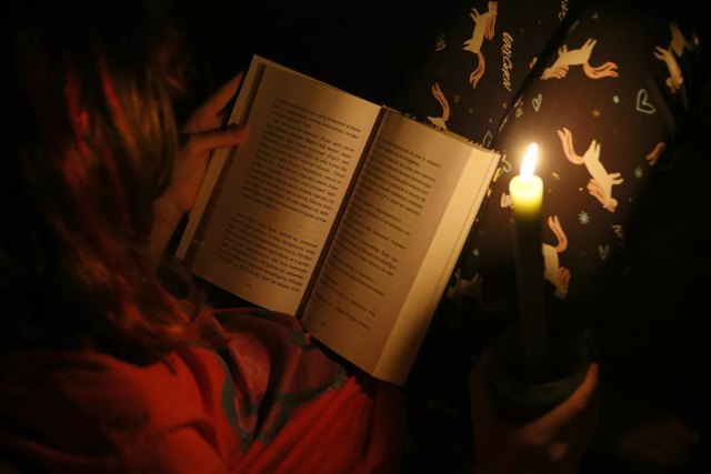 Trẻ em đọc sách dưới ánh nến khi thử nghiệm cắt điện ở Kiev.