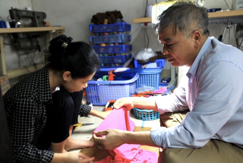 &Ocirc;ng Đỗ Minh T&aacute;m đang nhiệt t&igrave;nh chỉ dạy ch&aacute;u L&ecirc; Thị Thu Huyền học may &aacute;o d&agrave;i