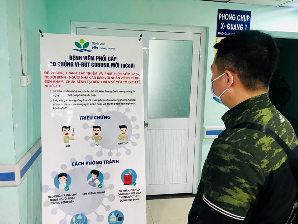 Người nhà bệnh nhân được phát khẩu trang và đang đọc tuyên truyền về dịch nCoV tại BV Nhi TW.