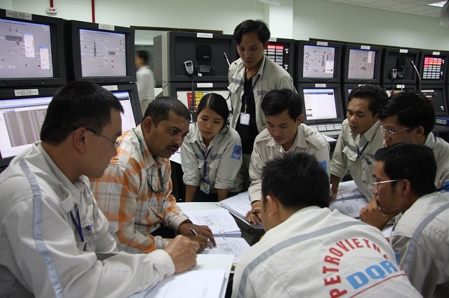 Nữ kỹ sư Phạm Minh Hòa được chuyên gia người nước ngoài hướng dẫn vận hành hệ thống điều khiển NMLD Dung Quất lúc chạy thử (commissioning).